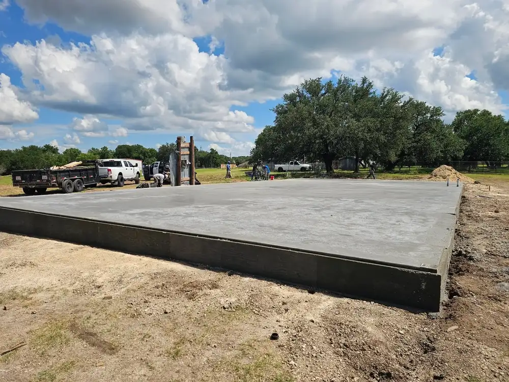 A large finished concrete slab with clean formed edges poured on a cleared lot